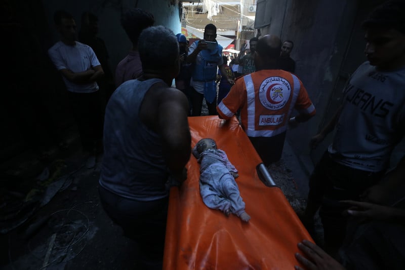 paramedics carry a stretcher with the body of a baby