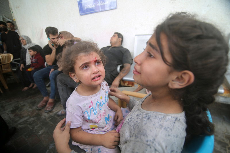 A crying toddler and a young girls wait for medical attention