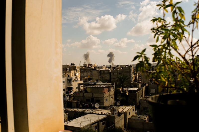 From a window, smoke can be seen rising in the distance