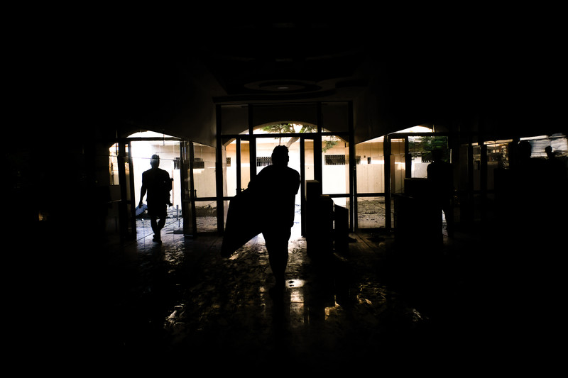 People in silhouette carrying bags from a damaged building.
