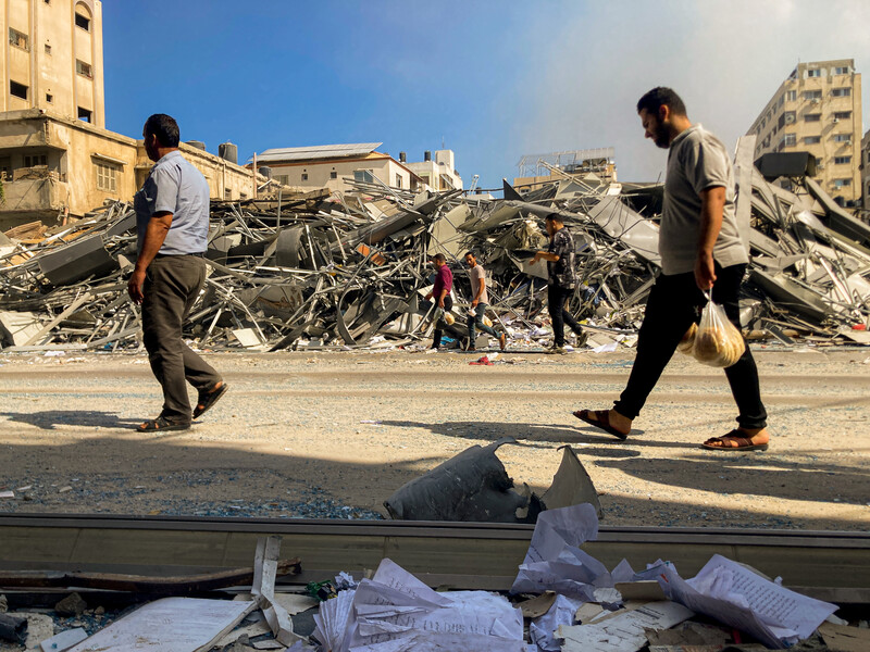 Men walk past a building completely destroyed in an airstrike