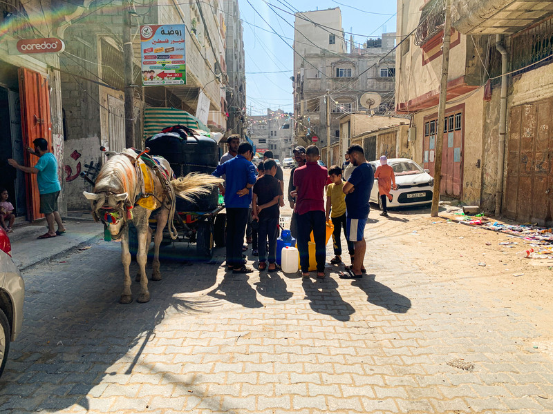 People gather around a horse-drawn car delivering water