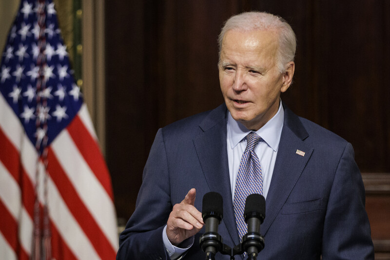 President Joe Biden stands at presidential podium with a US flag next to him