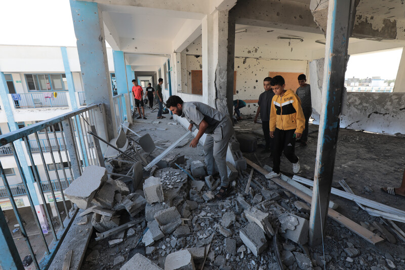 Men and children sift through rubble on the third floor of a damaged building