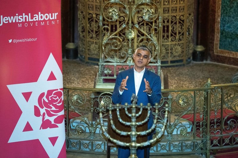 Mayor of London Sadiq Khan stands at a podium next to a sign reading "Jewish Labour Movement"