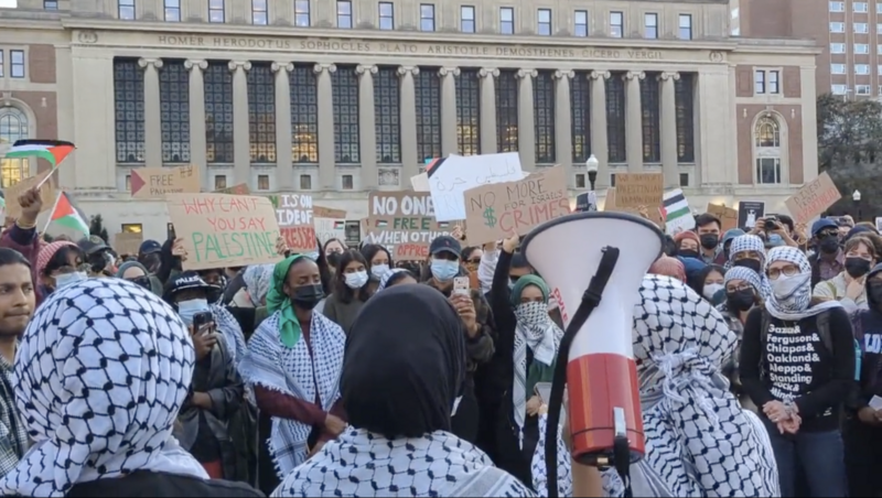 Students wearing traditional Palestinian scarves and holding signs and bullhorns protest on Columbia University's campus