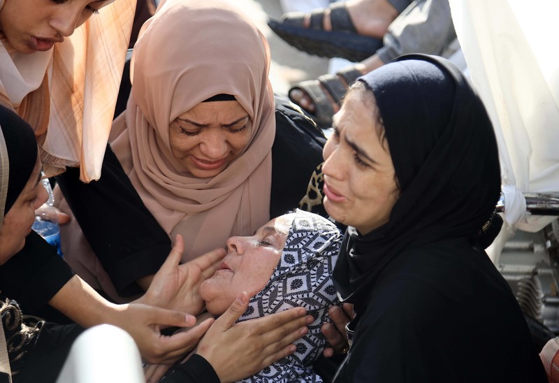 Three Palestinian women and a child comforting a woman