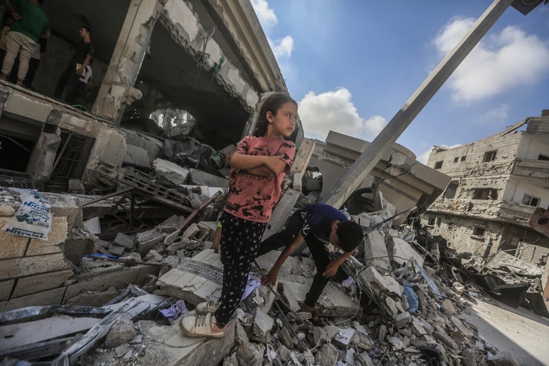 Young girl stands defiantly amid the ruins of a building
