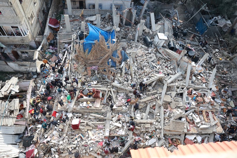 People search the rubble of a bombed building with personal effects strewn about 