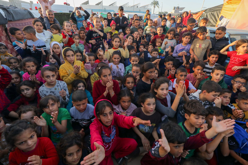 A crowded lot full of children waving their arms in a group activity