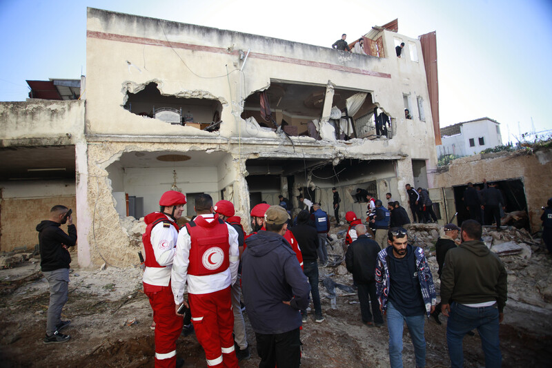 People and uniformed civic workers check the damage to a shelled house 