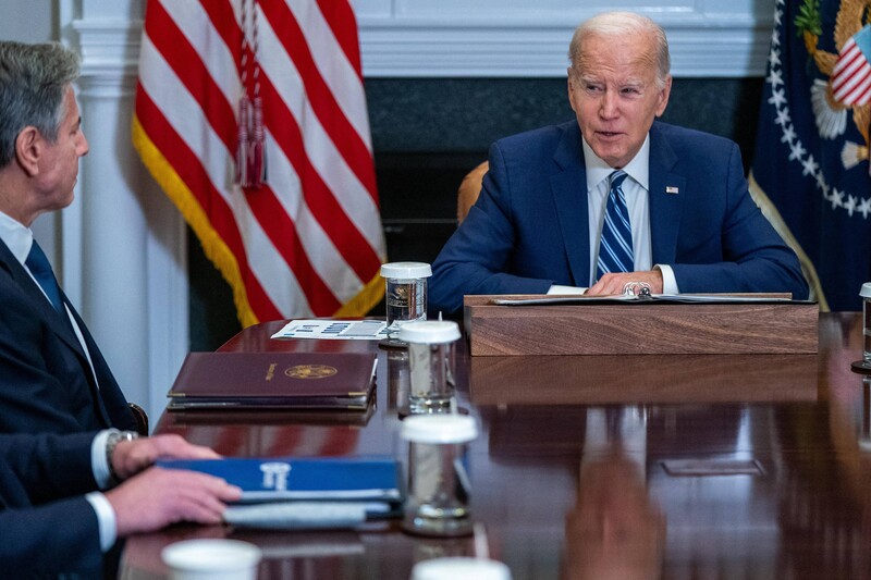 Joe Biden and Antony Blinken seated with an American flag between them