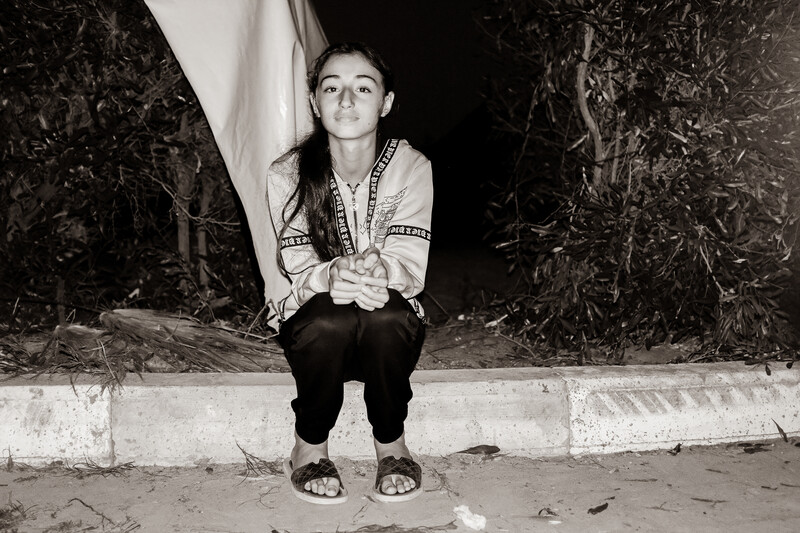 A girl sits on a pavement stone