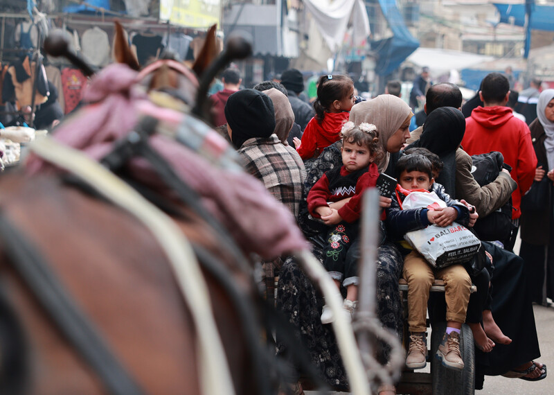 A busy street with children and horse drawn carriages