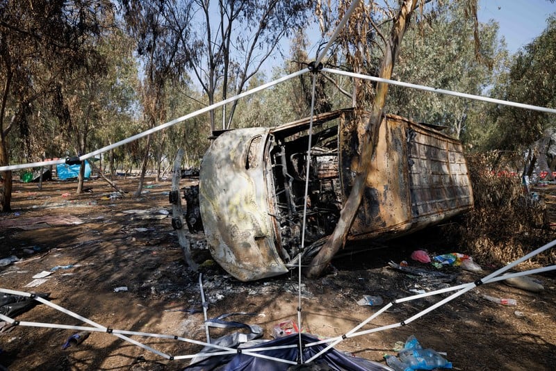 Burned out, overturned bus lies amid debris and trees