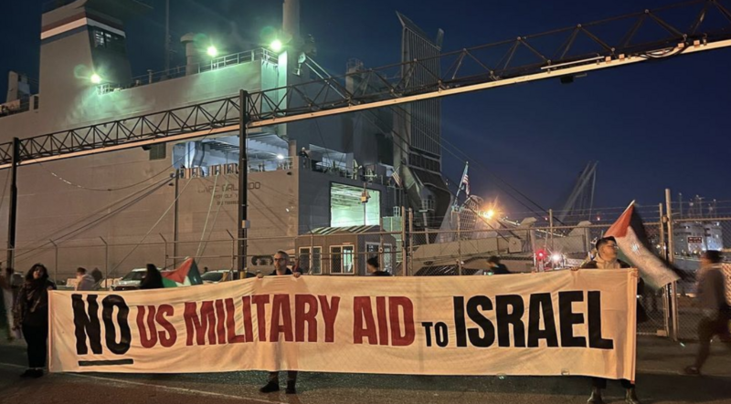 Activists hold a banner that reads No Military Aid to Israel in front of a large cargo ship