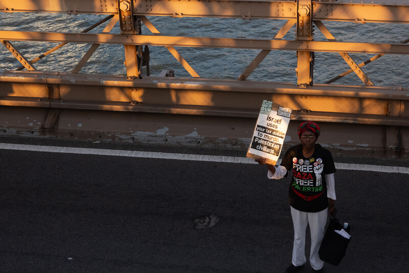 A woman stands alone with a placard