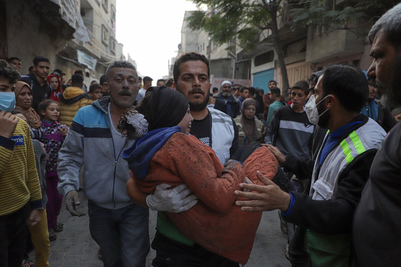 An injured Palestinian is carried as people look on