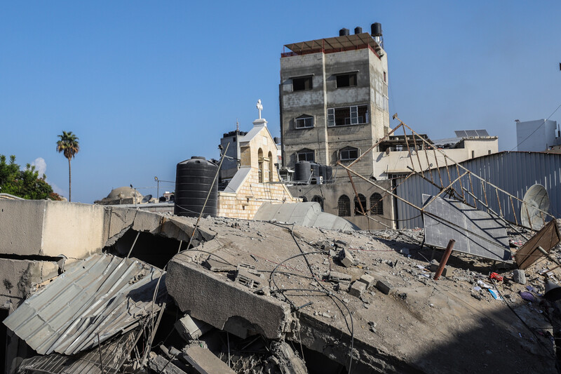 A destroyed building with a cross visible lies in ruins