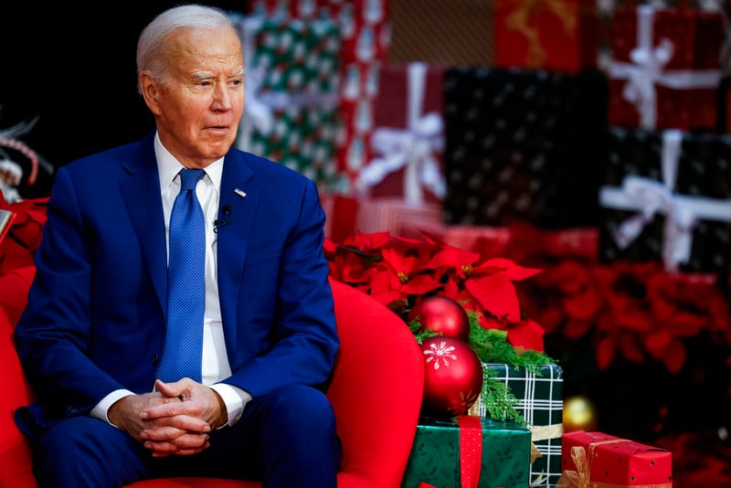 President Joe Biden sits in a red chair with wrapped boxes nearby