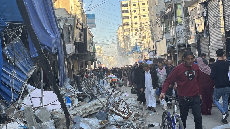 People crowd through a cityscape in ruins