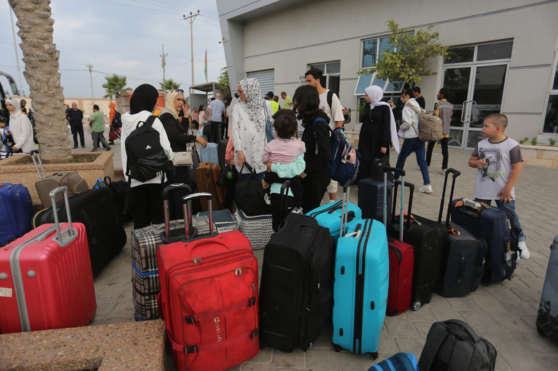 People with suitcases stand at the Rafah crossing 