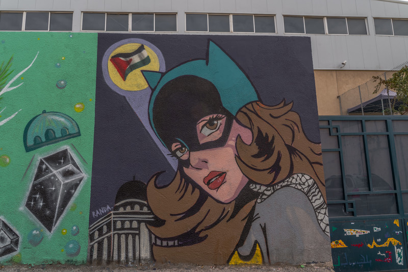 A mural of Batgirl and the bat signal painted as the Palestinian flag over al-Aqsa Mosque