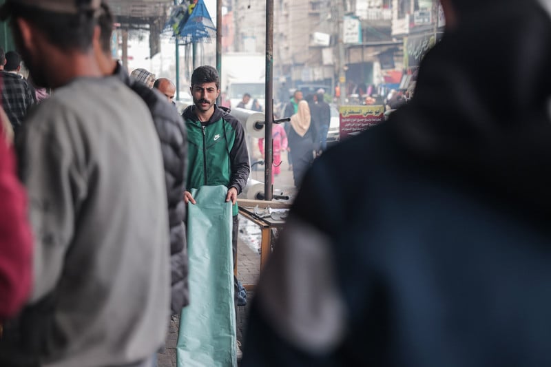 A man walks with a plastic sheet in a crowded street