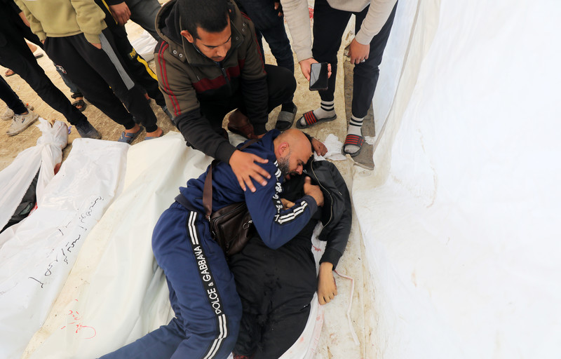 A man cries next to the body of his son