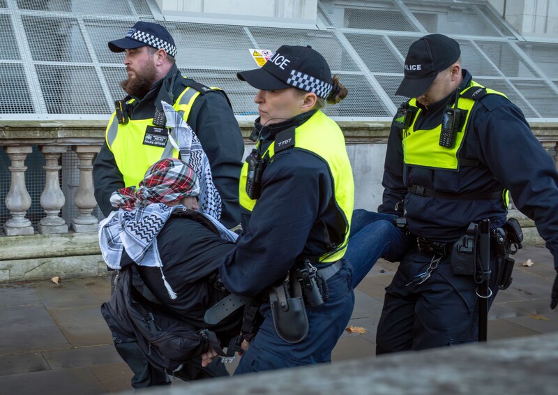 Three British police officers carry a demonstrator away