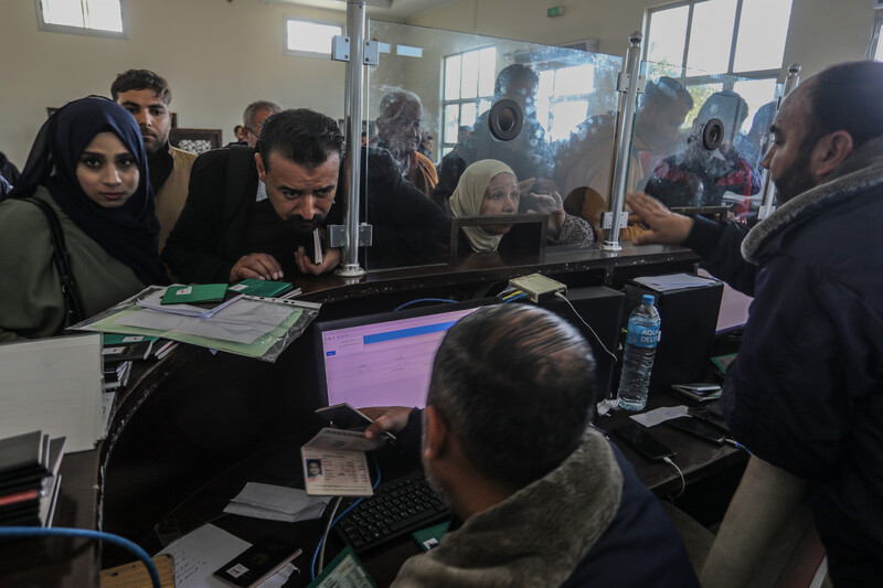 People crowd a window at a passport terminal