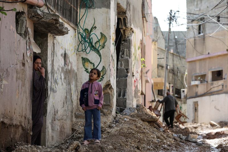 Girl and woman stand near the debris of destroyed infrastructure