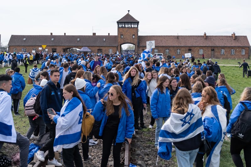 School children stand draped in Israeli flags outside Auschwitz