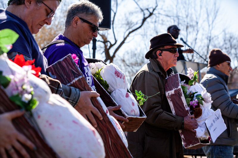 People hold fake children's coffins