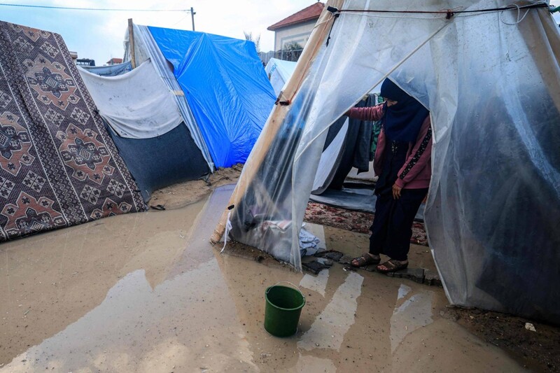 A woman stand ankle deep in brackish water in a tent