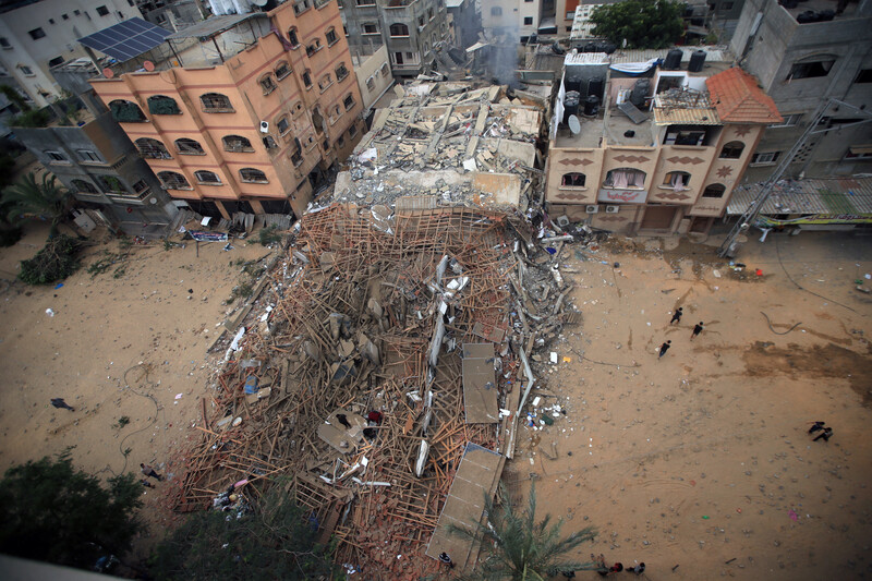 Aerial view shows completely leveled and debris-strewn area in between two multi-story buildings