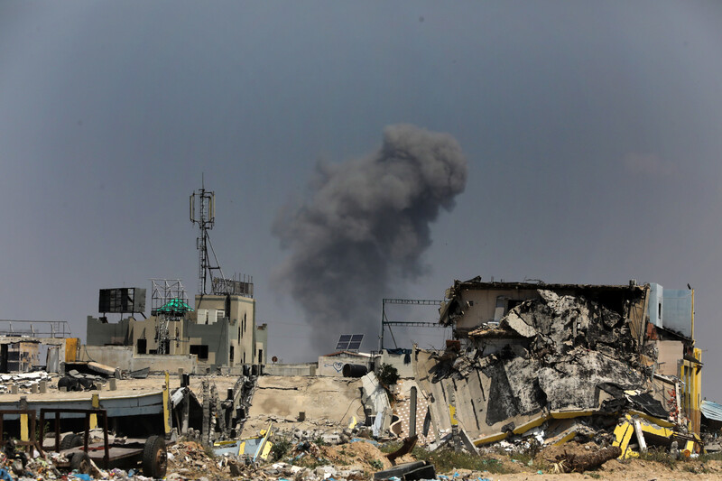 A plume of smoke from an Israeli airstrike rises from a horizon of destroyed buildings