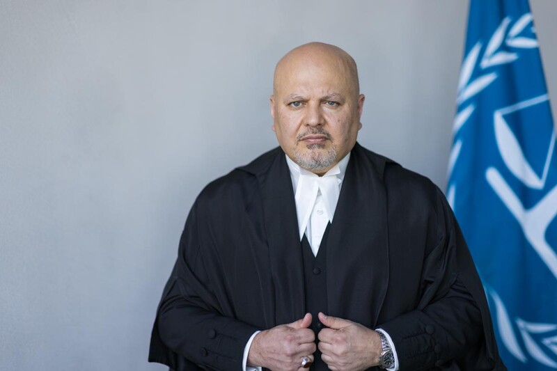 Portrait of Karim Khan in judicial robes next ICC flag