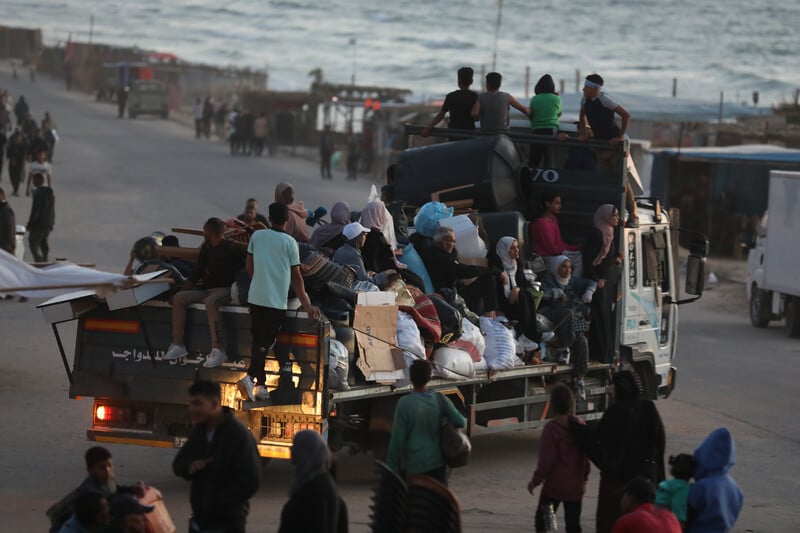 families on the back of a truck with their possessions