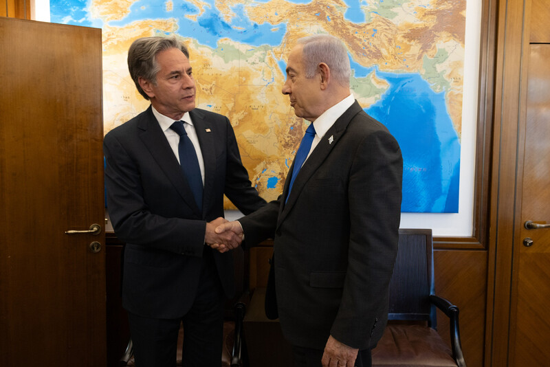 Secretary of State Antony Blinken shakes hands with Israeli Prime Minister Benjamin Netanyahu with a map behind them