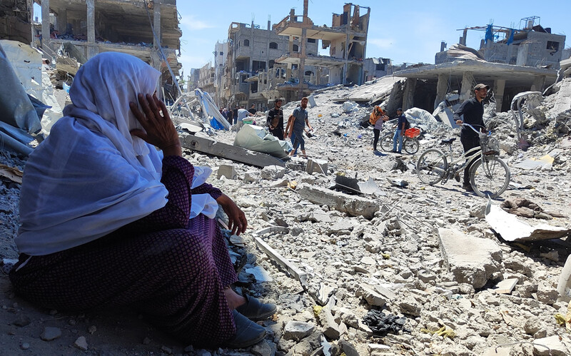 A woman is seated and is overlooking the rubble and debris around her 