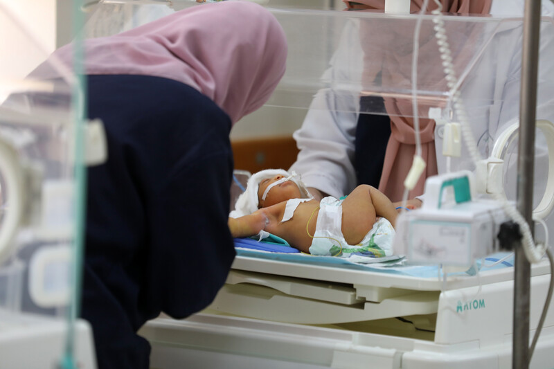 A woman leans over a baby