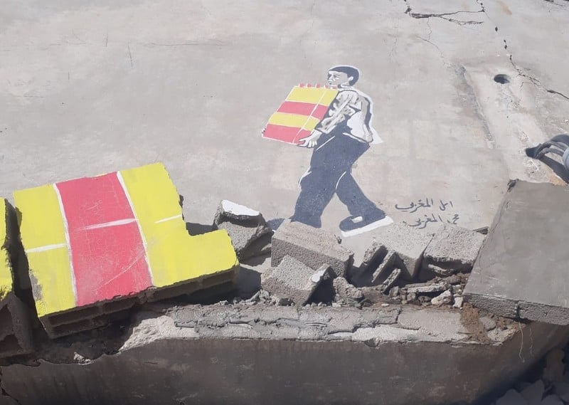 A colorful graffiti depicts a man carrying building blocks