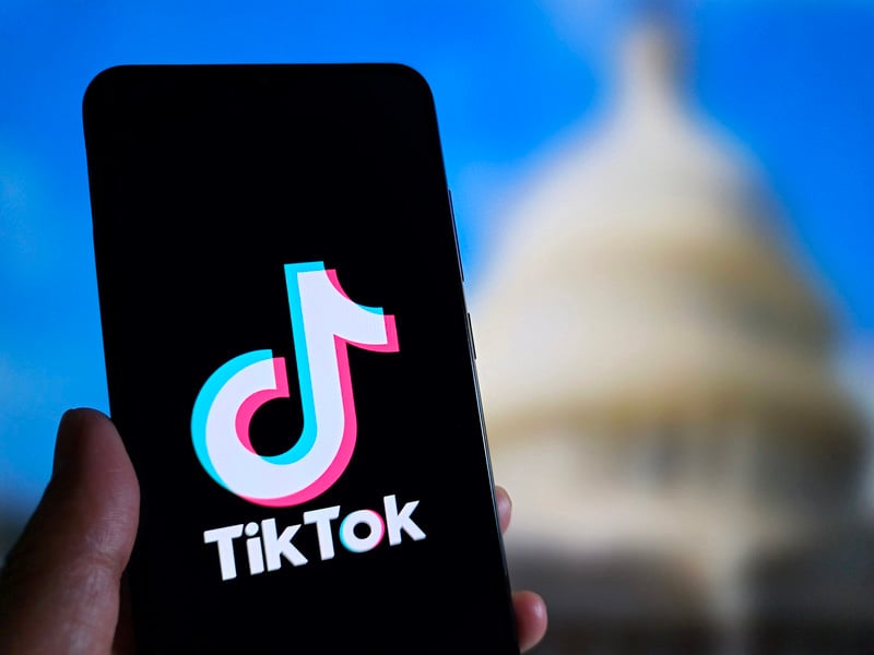 A TikTok logo is in front of a blurred image of the US Congress