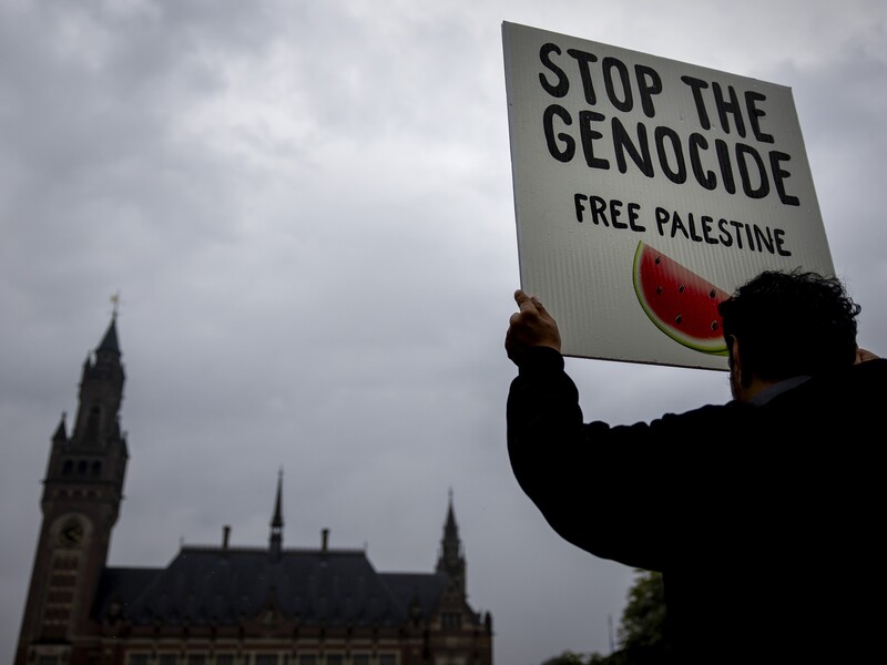 A man holds a sign saying "Stop the genocide: Free Palestine" outside the International Court of Justice