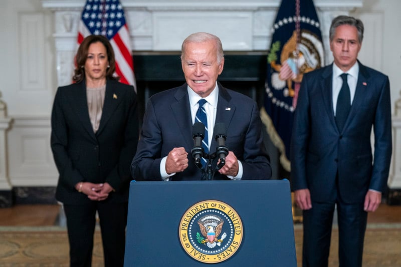 President Joe Biden speaks in the State Dining Room of the White House with Vice President Kamala Harris and Secretary of State Tony Blinken behind him 