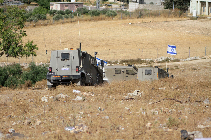 Israeli armored vehicles and Israeli flag in a field 