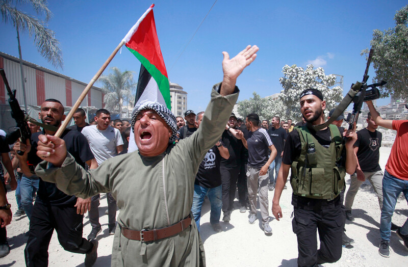 Palestinians carry weapons, flag during a funeral march 