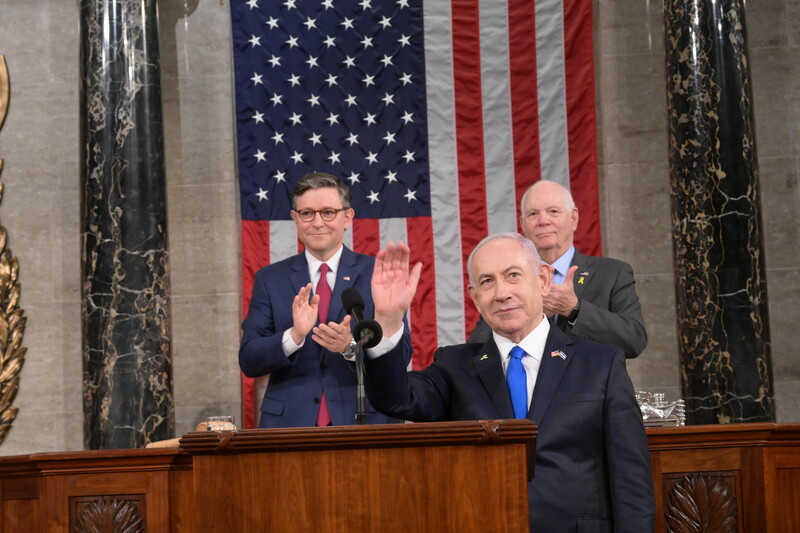 Benjamin Netanyahu stands in front of Mike Johnson, Ben Cardin and American flag