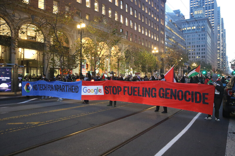 Demonstrators block a street with two large banners 